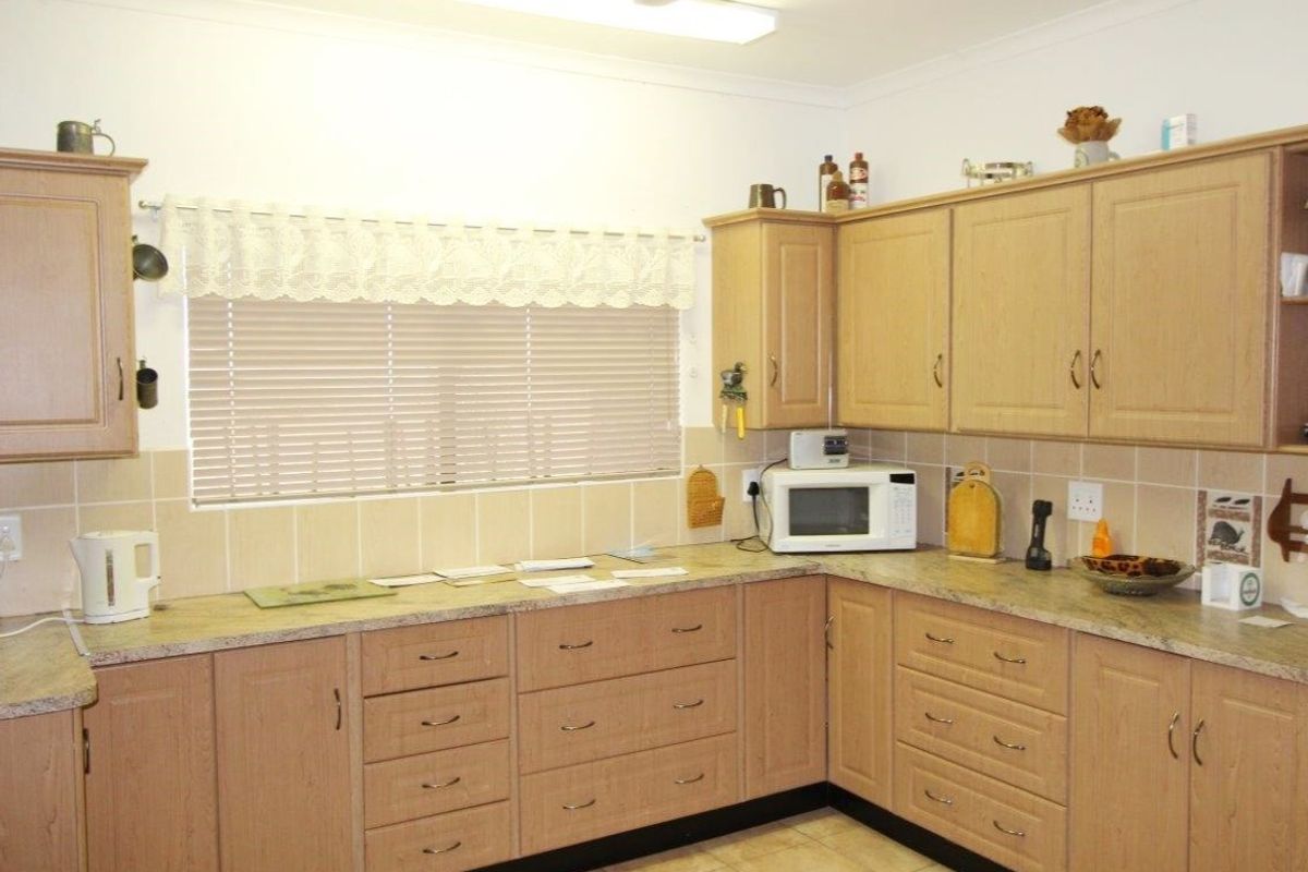 A functional kitchen featuring light wood cabinetry, laminate countertops, tiled splashbacks, and tiled flooring, providing ample storage and workspace.
