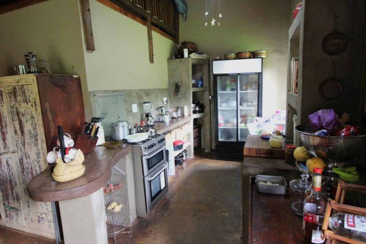 Rustic farm-style kitchen featuring built-in concrete countertops, a freestanding oven, and an open-plan layout with a mezzanine level above.