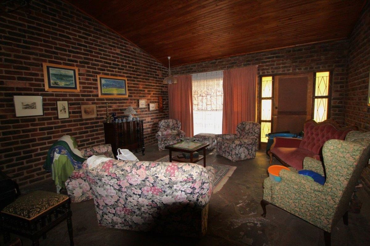 A rustic living room featuring exposed face-brick walls, a high timber-clad vaulted ceiling, and direct access to the exterior through a glass-paneled door.