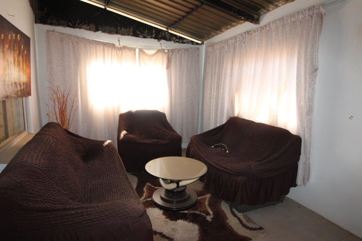 A living area featuring exposed roof structure and visible signs of ceiling damage, requiring maintenance and repair to improve the space.
