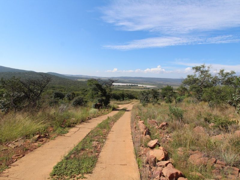 A scenic view overlooking the natural landscape and valley from an unpaved access track on the residential property.