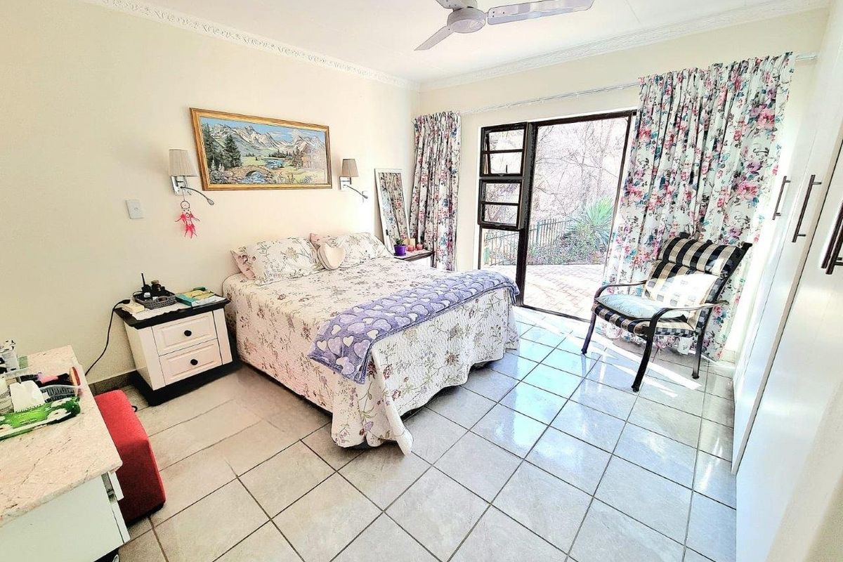 A bedroom featuring tiled flooring, a ceiling fan, and direct access to an outdoor patio area through a glass door.