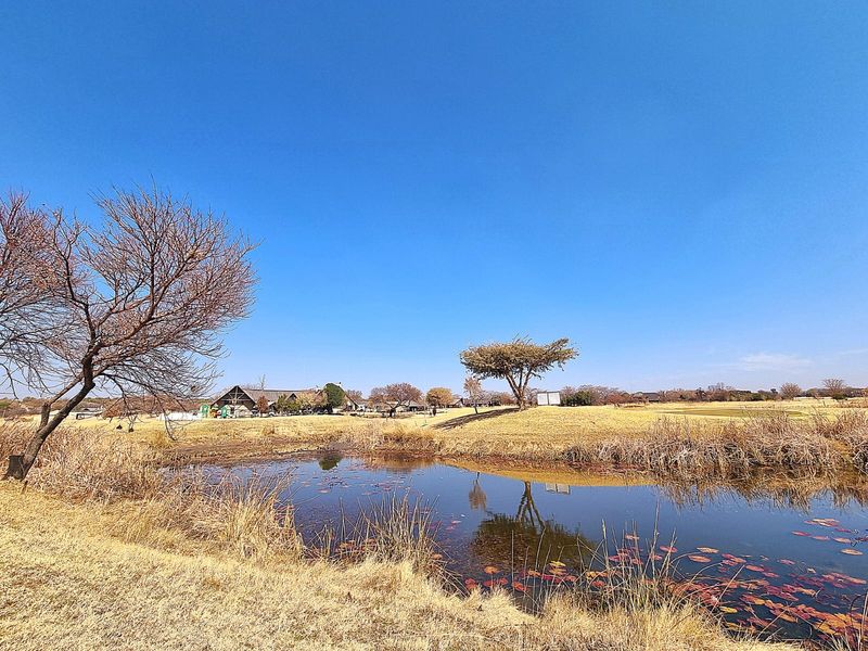 A scenic view of a natural pond and landscaped grounds within the residential estate, showcasing the open space and surrounding environment.