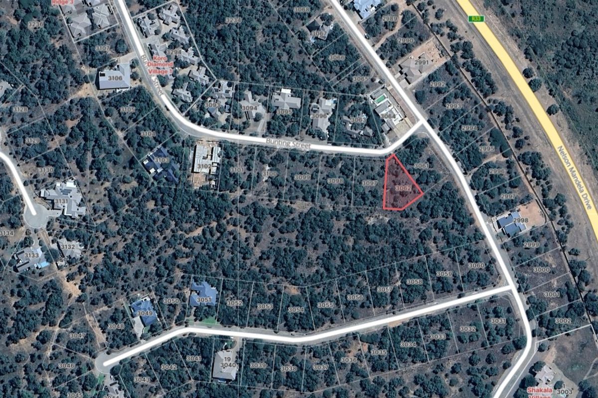 Aerial view of a vacant residential plot highlighted in red, situated within a developed estate with established vegetation.