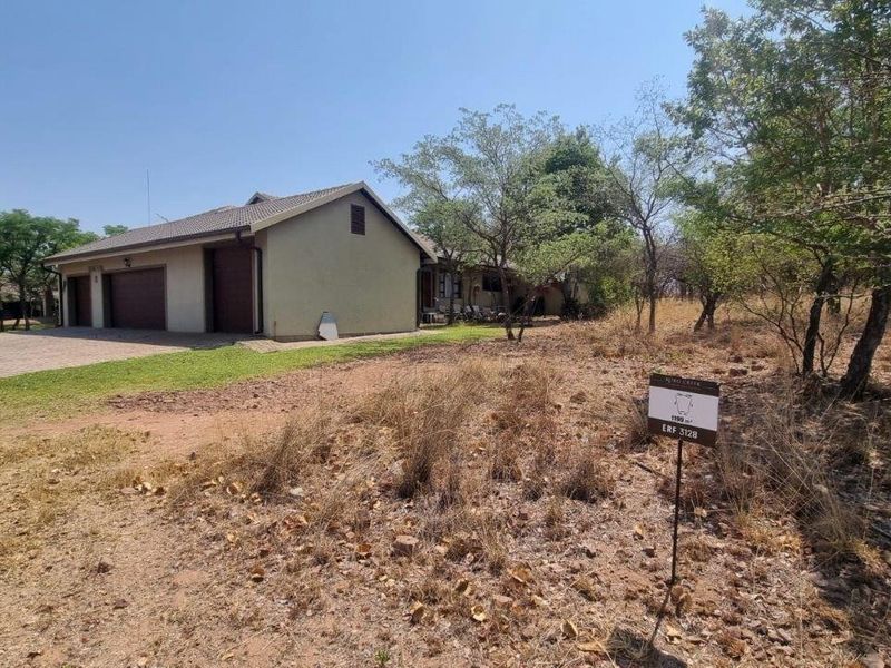 A view of a residential vacant land plot featuring a paved driveway and an adjacent double garage structure.
