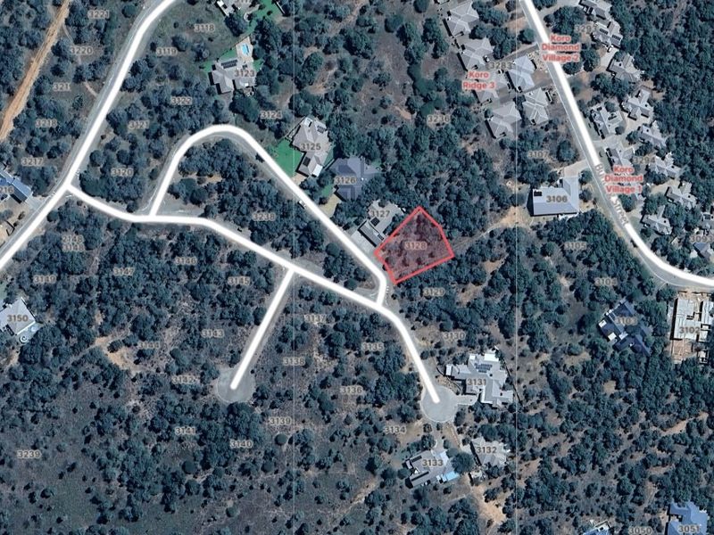 Aerial view of a vacant residential land plot situated within a developed estate, featuring established vegetation and direct access to paved roads.