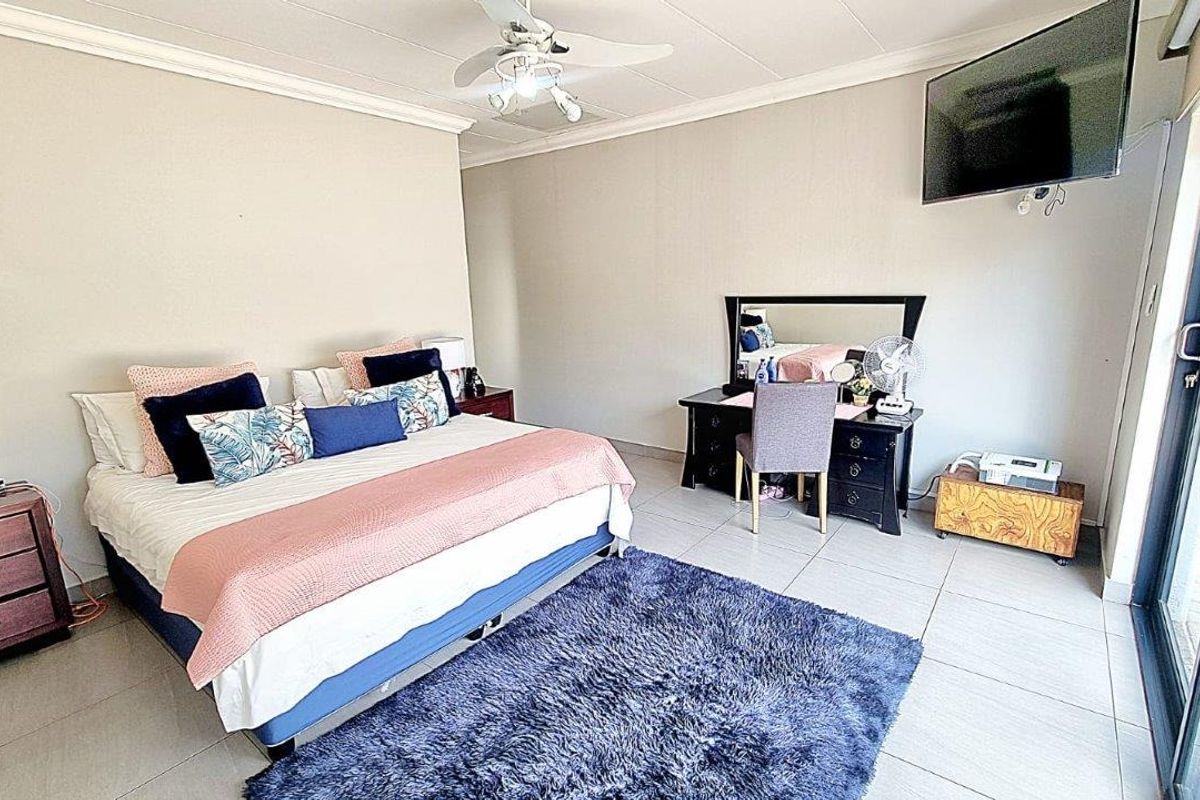 Spacious bedroom featuring tiled flooring, a ceiling fan, and sliding glass doors providing access to the exterior.