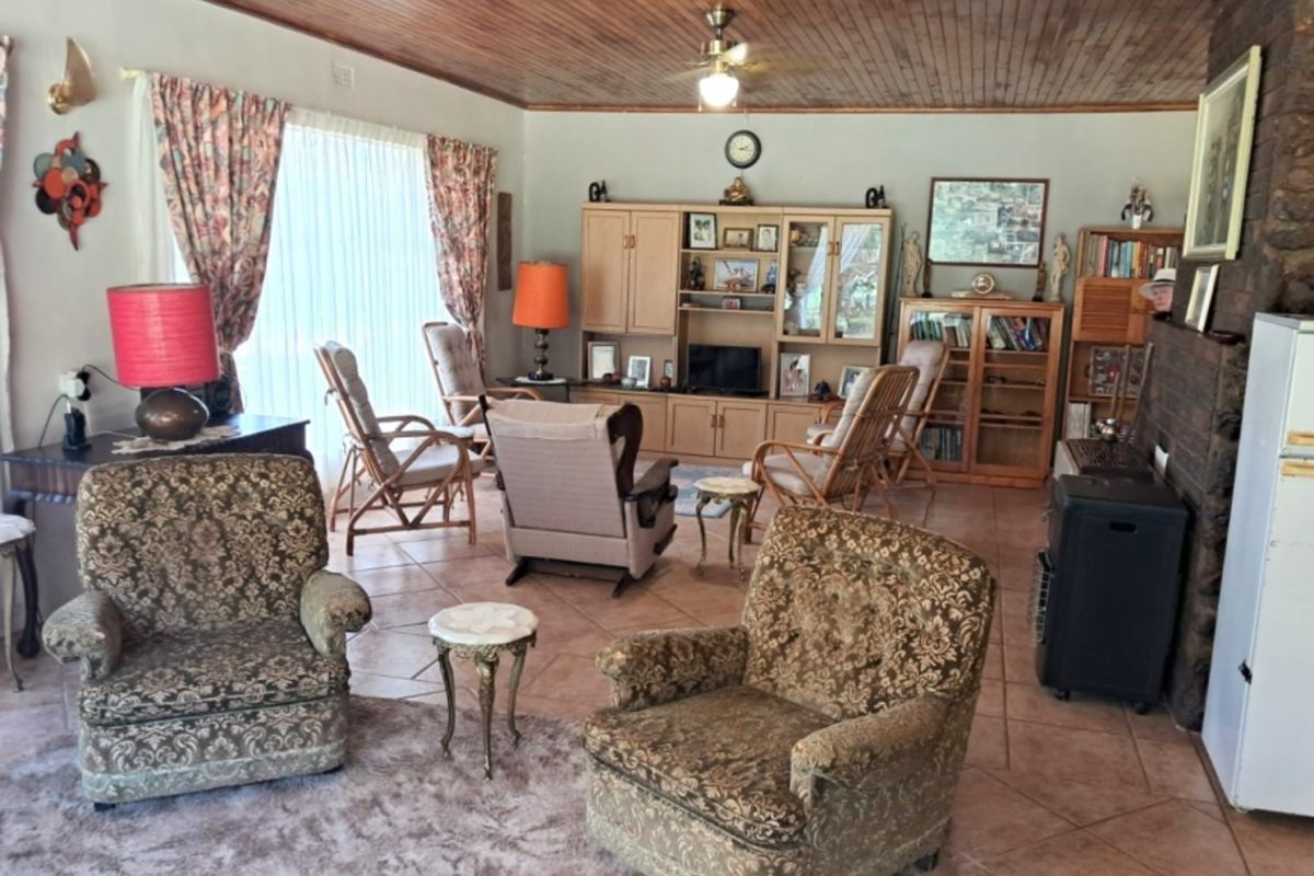 Spacious living room featuring a warm timber-clad ceiling, tiled flooring, and a prominent stone-clad fireplace, creating a cozy and traditional atmosphere.