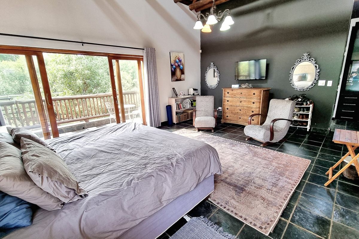 Spacious bedroom featuring vaulted ceilings, dark slate tile flooring, and large sliding glass doors opening onto a private balcony with scenic views.