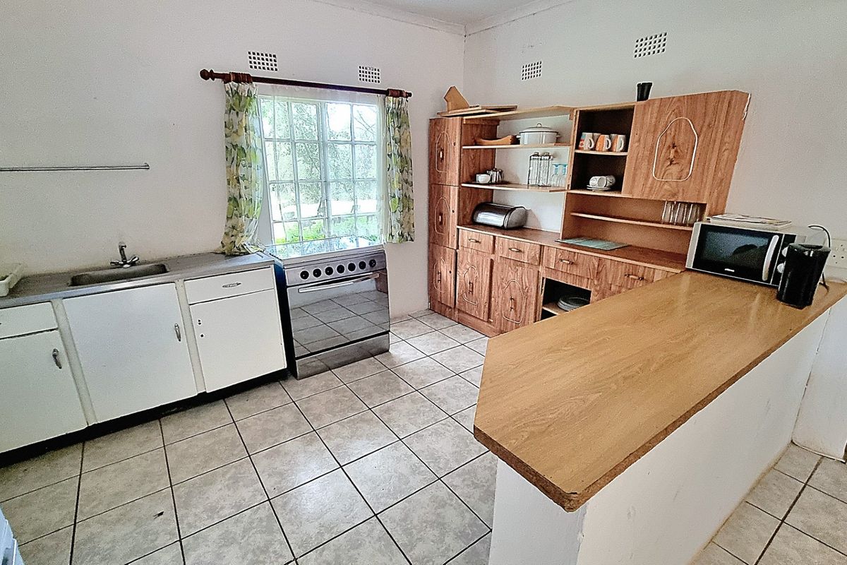 Functional kitchen featuring a breakfast bar, built-in wooden cabinetry, tiled flooring, and a freestanding stove with oven.