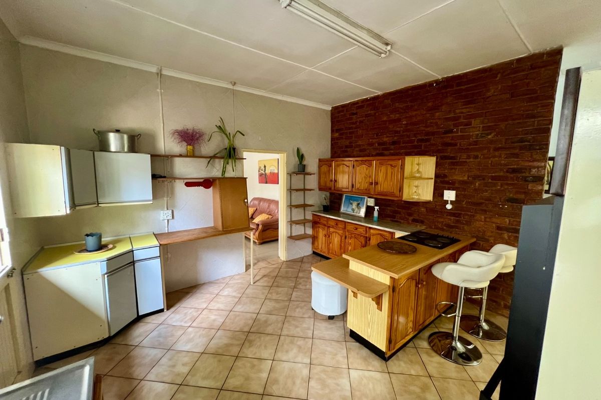 A functional kitchen featuring a mix of wooden and laminate cabinetry, a brick feature wall, and a central breakfast island with a built-in cooktop.