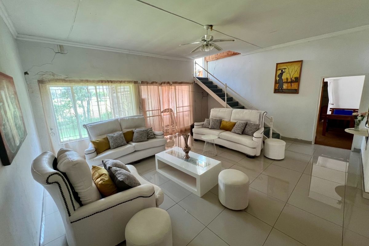 Spacious living room featuring large windows, tiled flooring, and an integrated staircase leading to the upper level.