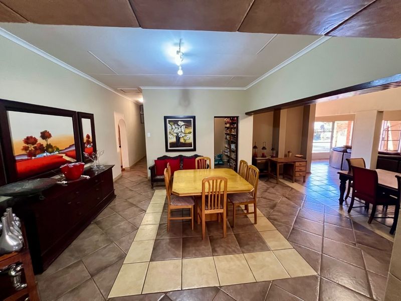 Spacious open-plan dining area featuring ceramic tile flooring, a decorative ceiling, and an adjacent pantry, offering a functional layout for family living.