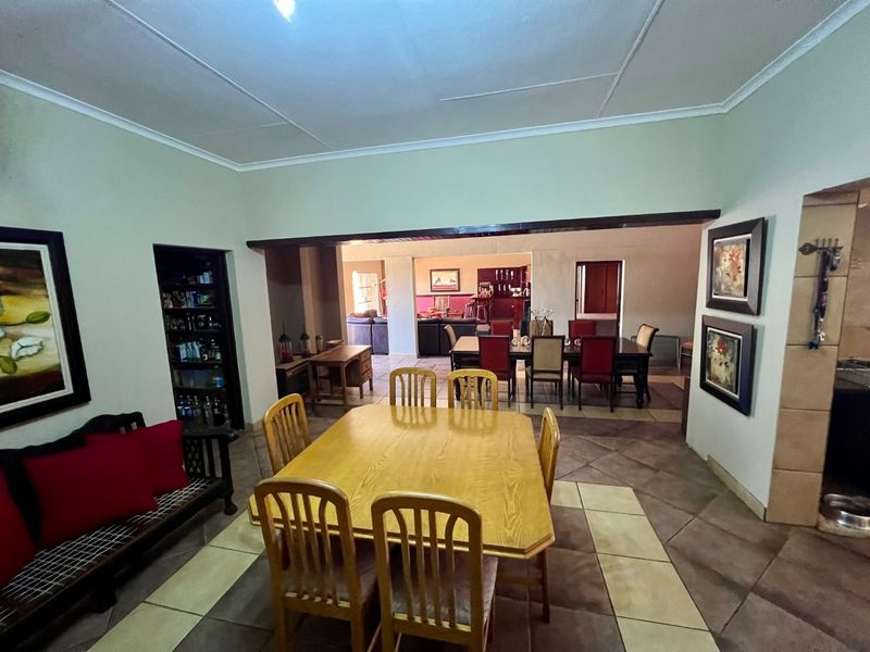 Spacious open-plan dining area featuring tiled flooring and built-in shelving, with a seamless transition into the adjacent living and bar spaces.