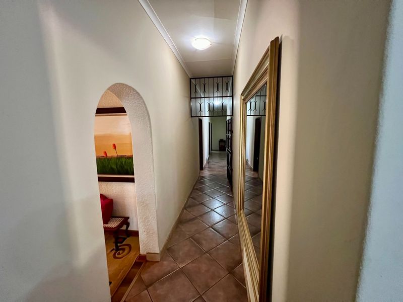 A tiled hallway featuring an arched entryway and a security gate, providing access to other areas of the home.