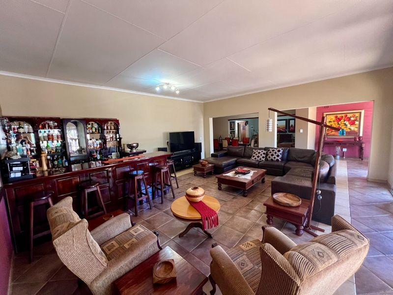 Spacious living area featuring a built-in wooden bar, tiled flooring, and an open-plan layout connecting to adjacent dining spaces.