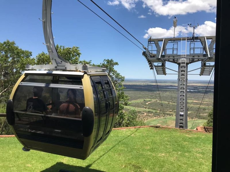A scenic view featuring a cable car system overlooking a vast landscape and golf course area.