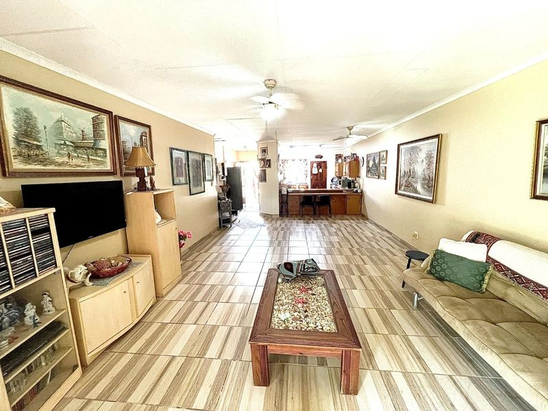 Spacious open-plan living and kitchen area featuring tiled flooring, ceiling fans, and a functional breakfast bar layout.