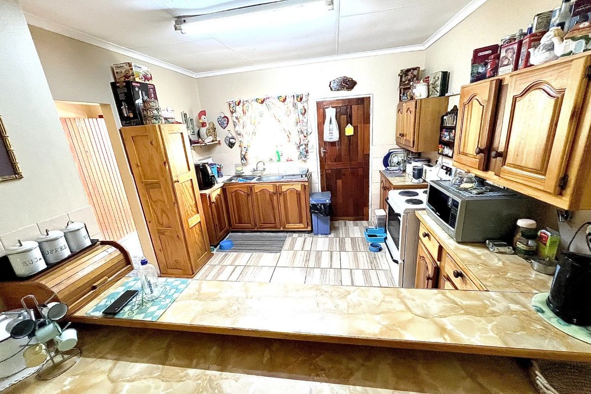 A functional kitchen featuring wooden cabinetry, laminate countertops, and tiled flooring, offering a traditional layout with potential for modern updates.