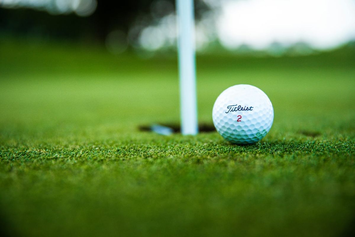 A close-up view of a golf ball on a putting green, highlighting the manicured landscape of the residential estate.