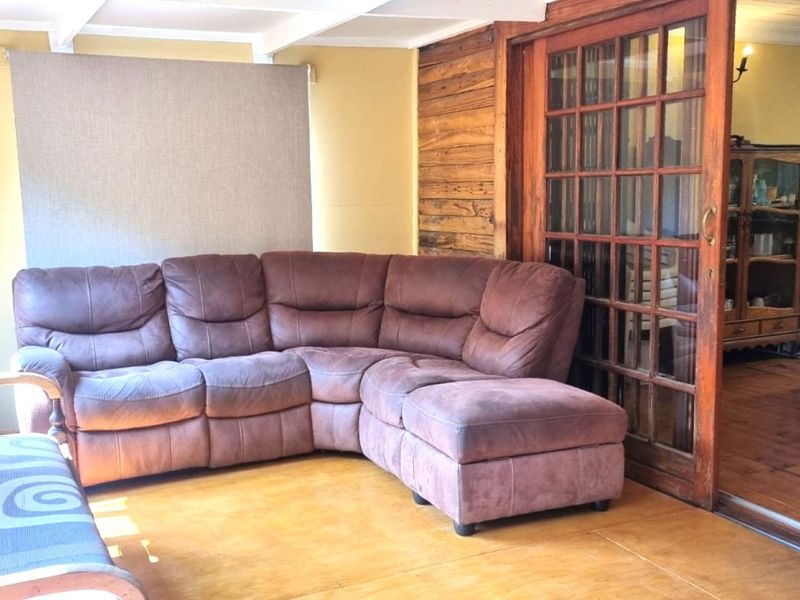 A covered patio area featuring timber wall cladding, exposed ceiling beams, and large timber sliding doors leading into the main living space.