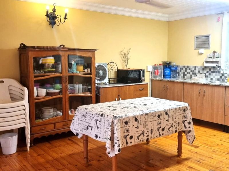 A functional kitchen featuring timber flooring, wooden cabinetry, tiled backsplash, and a stainless steel sink, offering a traditional and practical workspace.