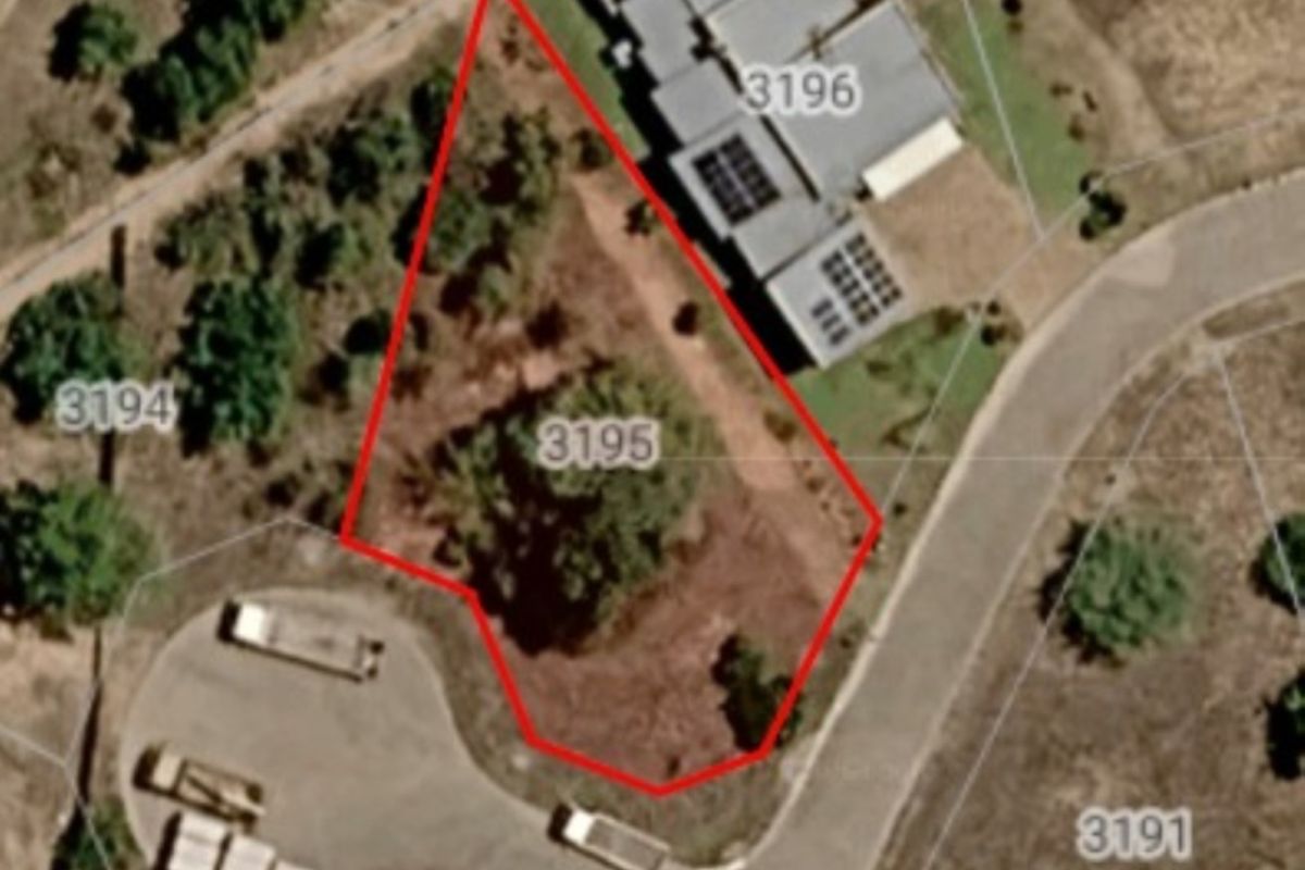 Aerial view of a vacant residential plot marked with boundary lines, situated in a developed neighborhood.