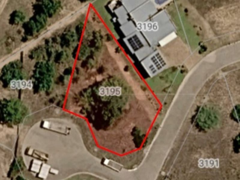 Aerial view of a vacant residential plot marked with boundary lines, situated in a developed neighborhood.