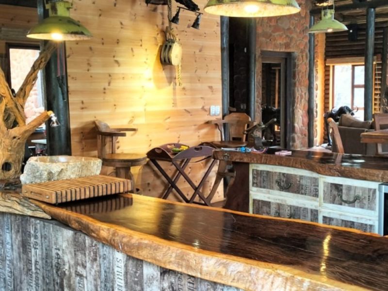Rustic kitchen featuring a unique live-edge timber breakfast bar, stone basin, and warm timber wall cladding, creating a distinctive lodge-style atmosphere.