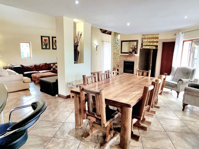 Spacious open-plan living and dining area featuring tiled floors, a built-in fireplace with stone detailing, and recessed lighting throughout.