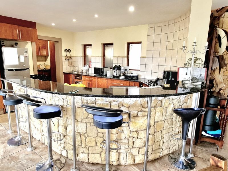 Spacious kitchen featuring a large stone-clad breakfast bar with granite countertop, ample cabinetry, and tiled finishes, creating a rustic yet functional culinary space.