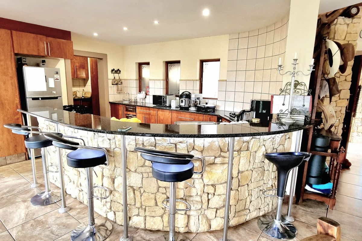 Spacious kitchen featuring a large stone-clad breakfast bar with granite countertop, ample cabinetry, and tiled finishes, creating a rustic yet functional culinary space.