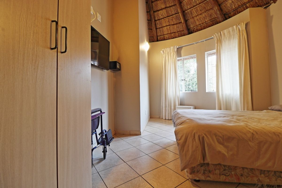 A bedroom featuring tiled flooring, a unique vaulted thatched roof ceiling, and built-in wardrobe storage.