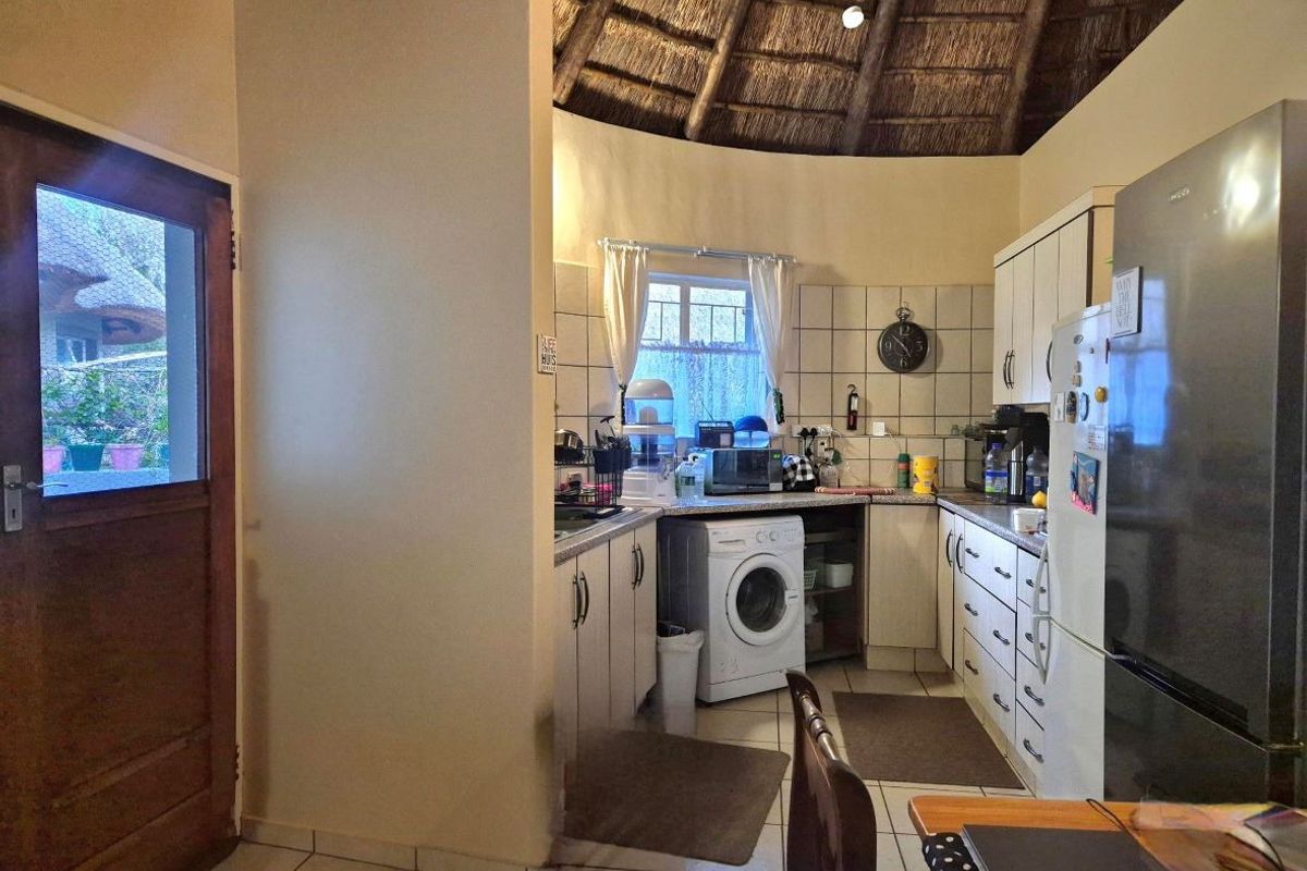 A functional kitchen featuring built-in cabinetry, tiled backsplash, and a unique vaulted thatch roof ceiling, with direct access to the exterior.