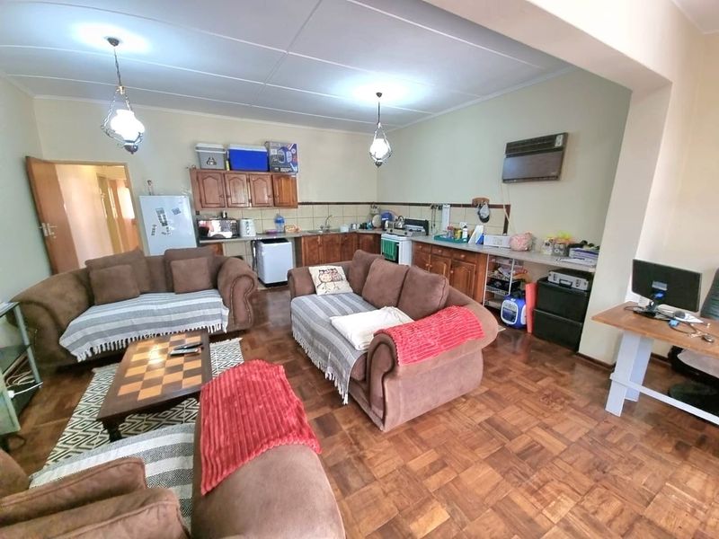 Open-plan living and kitchen area featuring traditional wooden parquet flooring, built-in cabinetry, and a tiled kitchen backsplash.