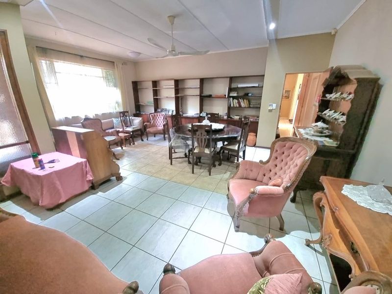 Spacious living and dining area featuring tiled flooring, built-in shelving units, and a ceiling fan.