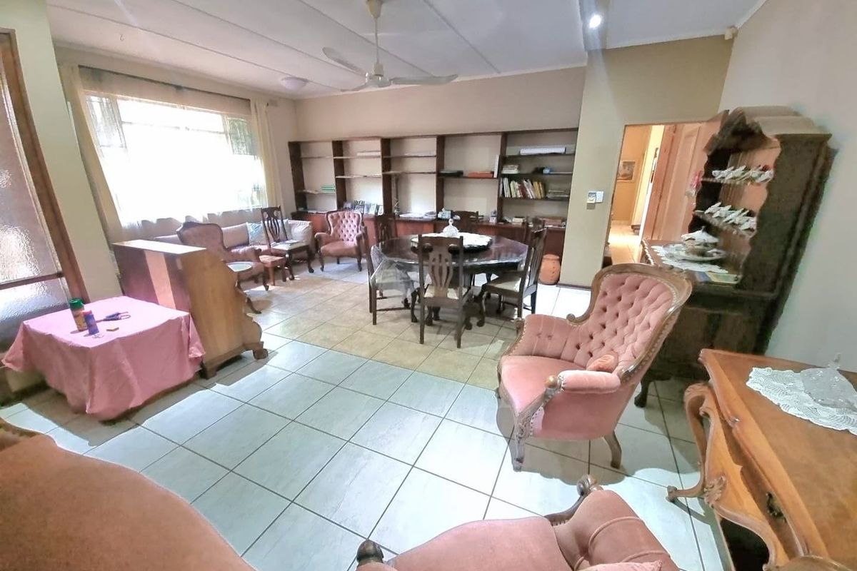 Spacious living and dining area featuring tiled flooring, built-in shelving units, and a ceiling fan.