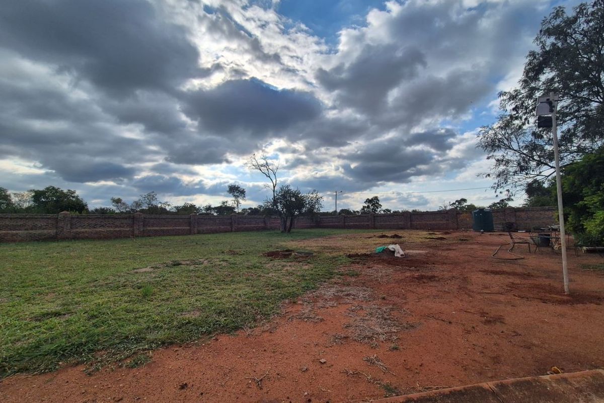 A spacious, level residential plot featuring a secure brick perimeter wall and an existing water storage tank, ready for development.