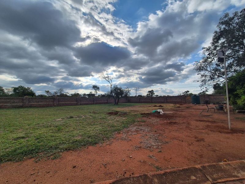 A spacious, level residential plot featuring a secure brick perimeter wall and an existing water storage tank, ready for development.