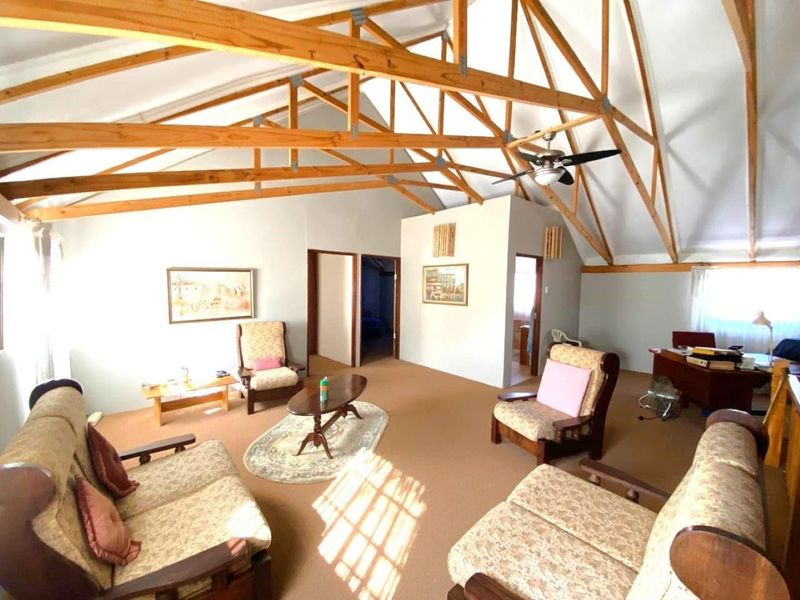 Spacious living area featuring a high vaulted ceiling with exposed timber roof trusses and a ceiling fan.