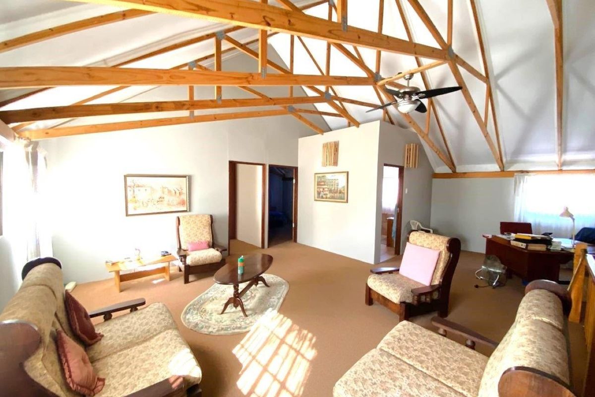 Spacious living area featuring a high vaulted ceiling with exposed timber roof trusses and a ceiling fan.