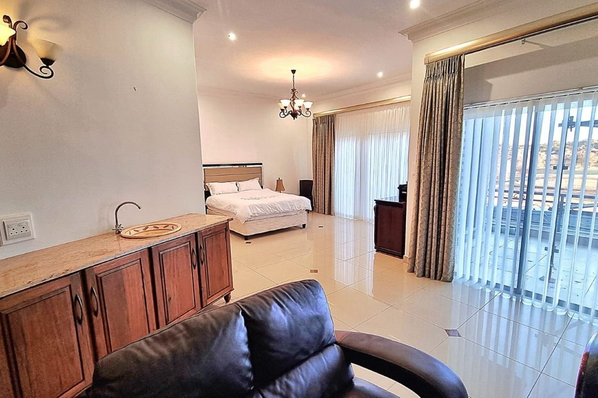Spacious bedroom featuring tiled flooring, built-in cabinetry with a sink, and large sliding glass doors providing access to an outdoor area.