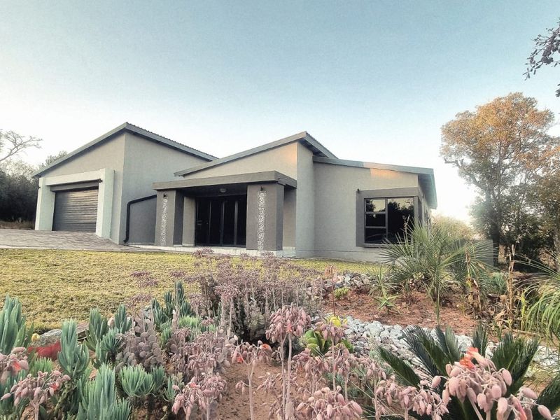 Modern single-story house featuring a contemporary facade, integrated garage, and well-maintained landscaped garden with native plants.