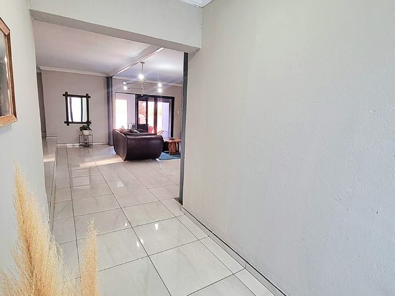 A bright, tiled hallway leading into an open-plan living area with large sliding glass doors providing natural light.