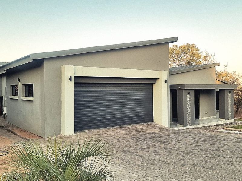 Modern single-story home featuring a sleek skillion roof, automated garage door, and a paved driveway leading to a covered entrance.