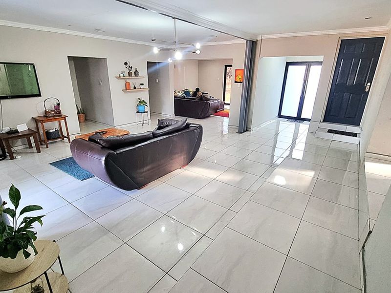 Spacious open-plan living area featuring large format floor tiles, neutral wall finishes, and direct access to outdoor space through sliding glass doors.