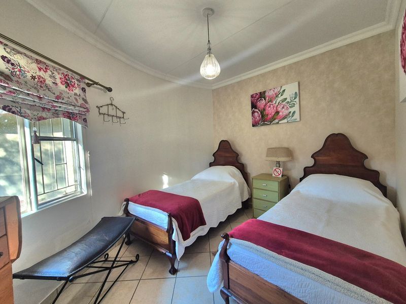 A well-maintained bedroom featuring tiled flooring, a coved ceiling, and a window with security bars, providing a functional and comfortable living space.