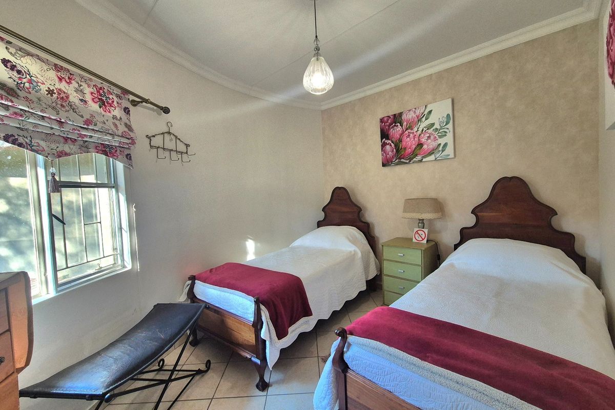 A well-maintained bedroom featuring tiled flooring, a coved ceiling, and a window with security bars, providing a functional and comfortable living space.