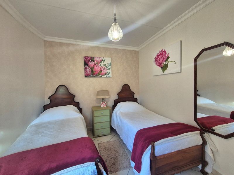 A bedroom featuring tiled flooring, ceiling cornice, and a central pendant light fixture.