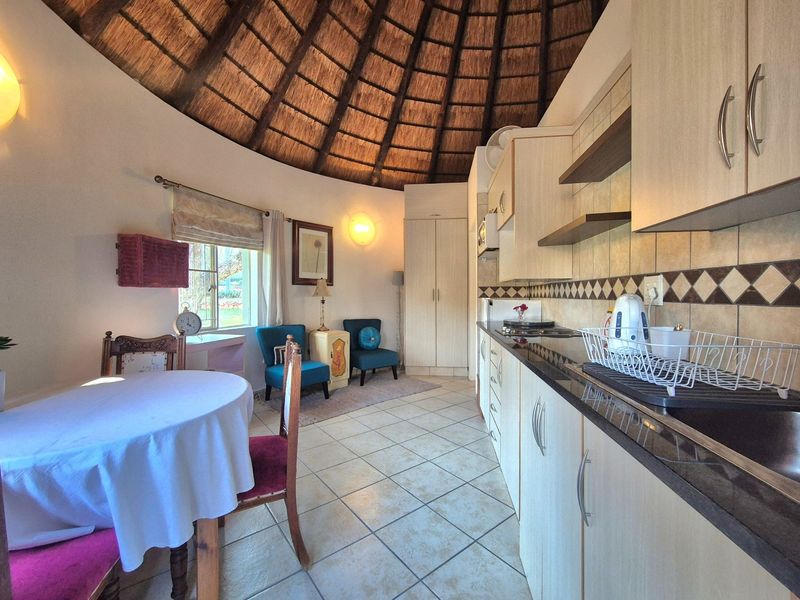 Open-plan kitchen and dining area featuring a unique vaulted thatched ceiling, tiled flooring, and modern built-in cabinetry with granite countertops.